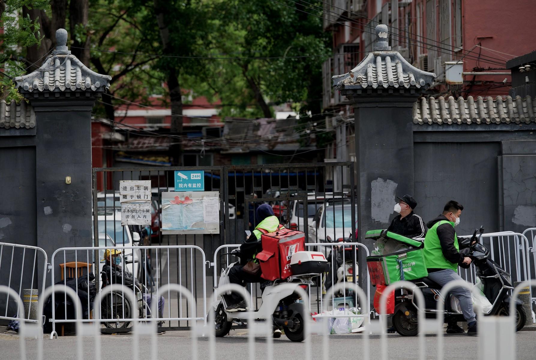 Food delivery workers wait outside the entrance of a locked-down residential area amid the Covid-19 pandemic in Beijing on April 28. Photo: AFP