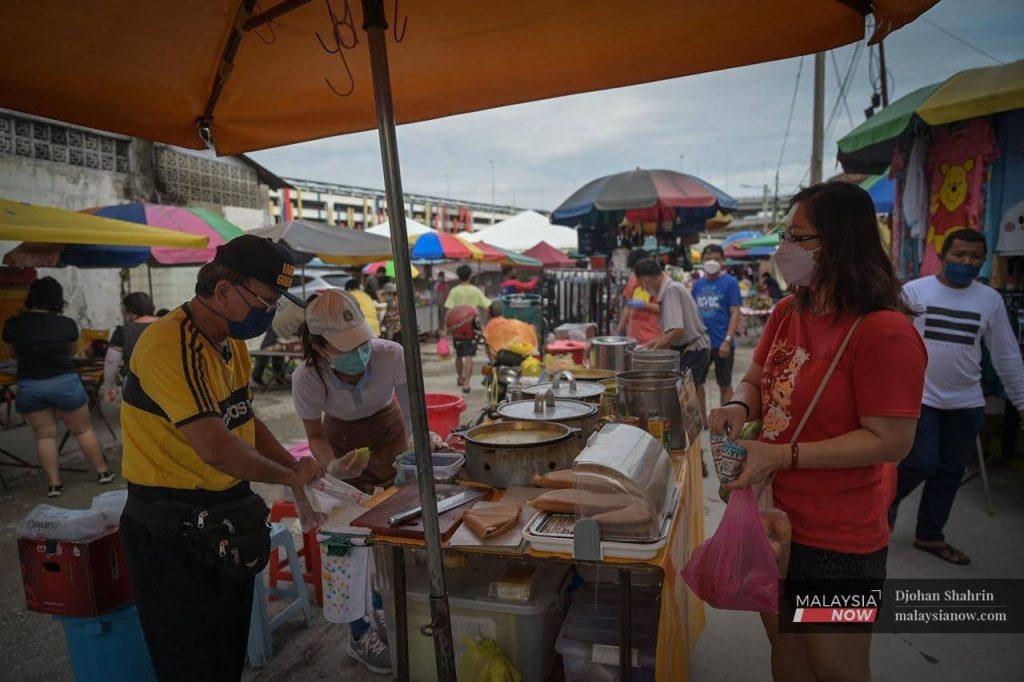 A customer waits as her order is wrapped at a stall selling apam balik in the Ampang market in Selangor.