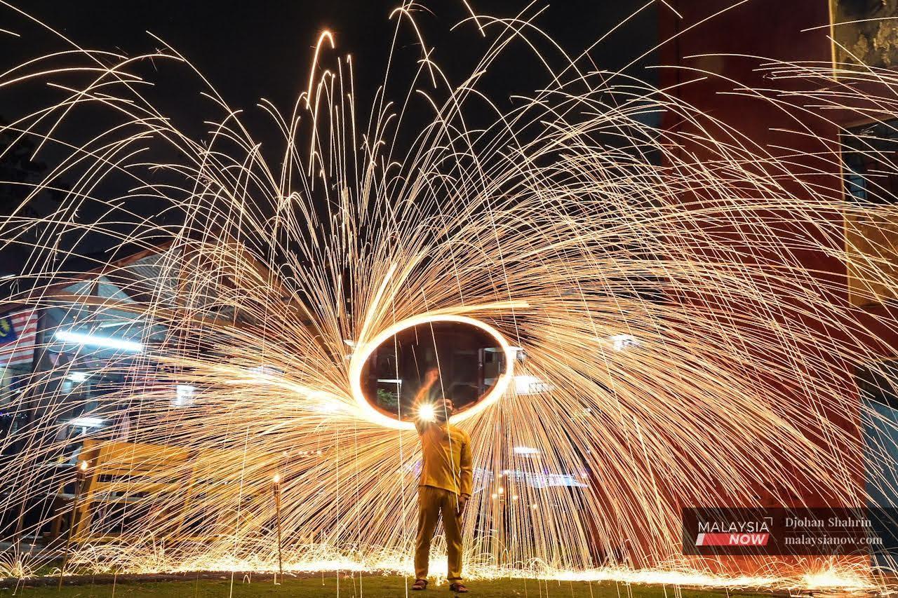 A man dressed in a traditional baju Melayu plays with a sprinkler ahead of Hari Raya at the Sri Melaka flats in Cheras.