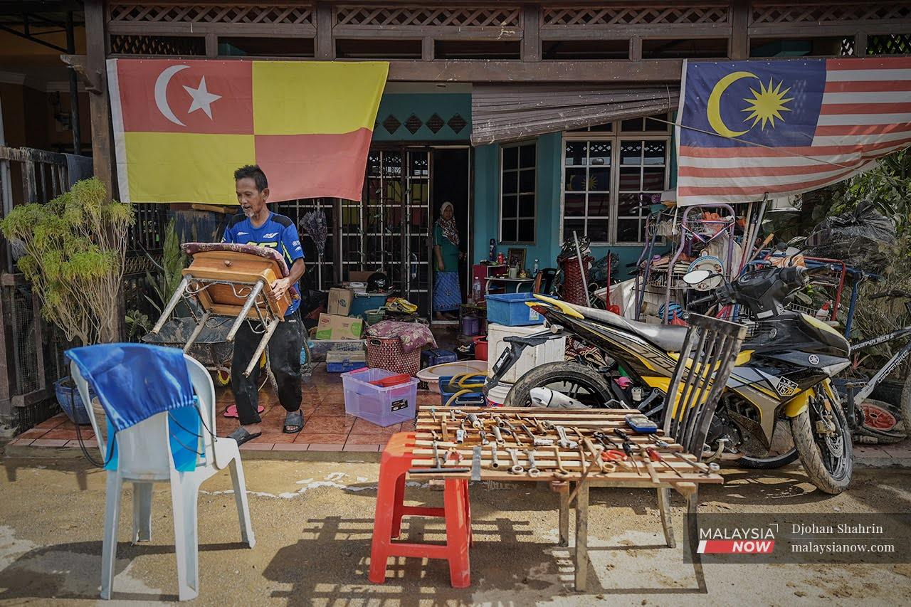A man carries furniture out to sun at his home in Taman Sri Nanding, Hulu Langat in Selangor, one of the states worst hit by the massive floods last December.