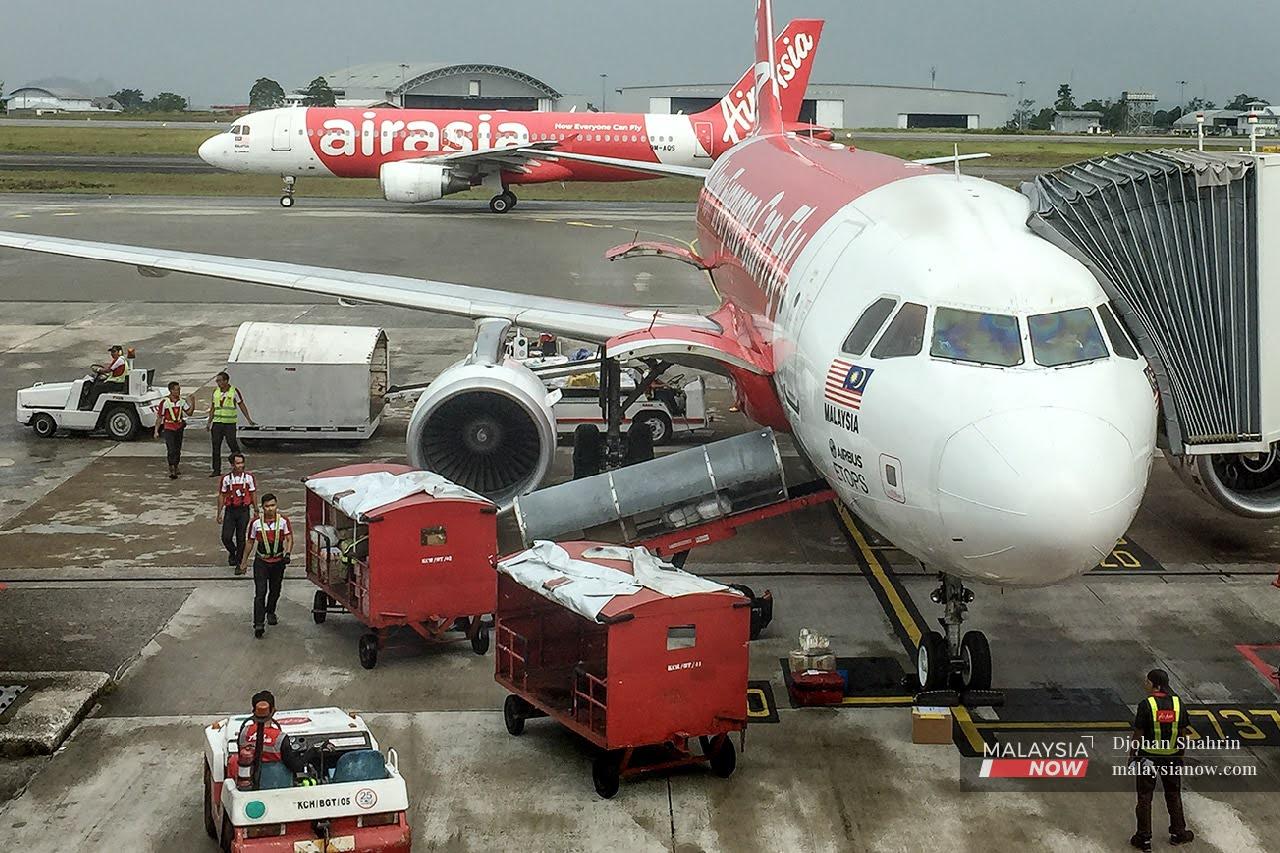 Ground crew conduct last-minute checks as baggage is loaded into the cargo hold of an AirAsia plane before take-off at klia2 in Sepang.
