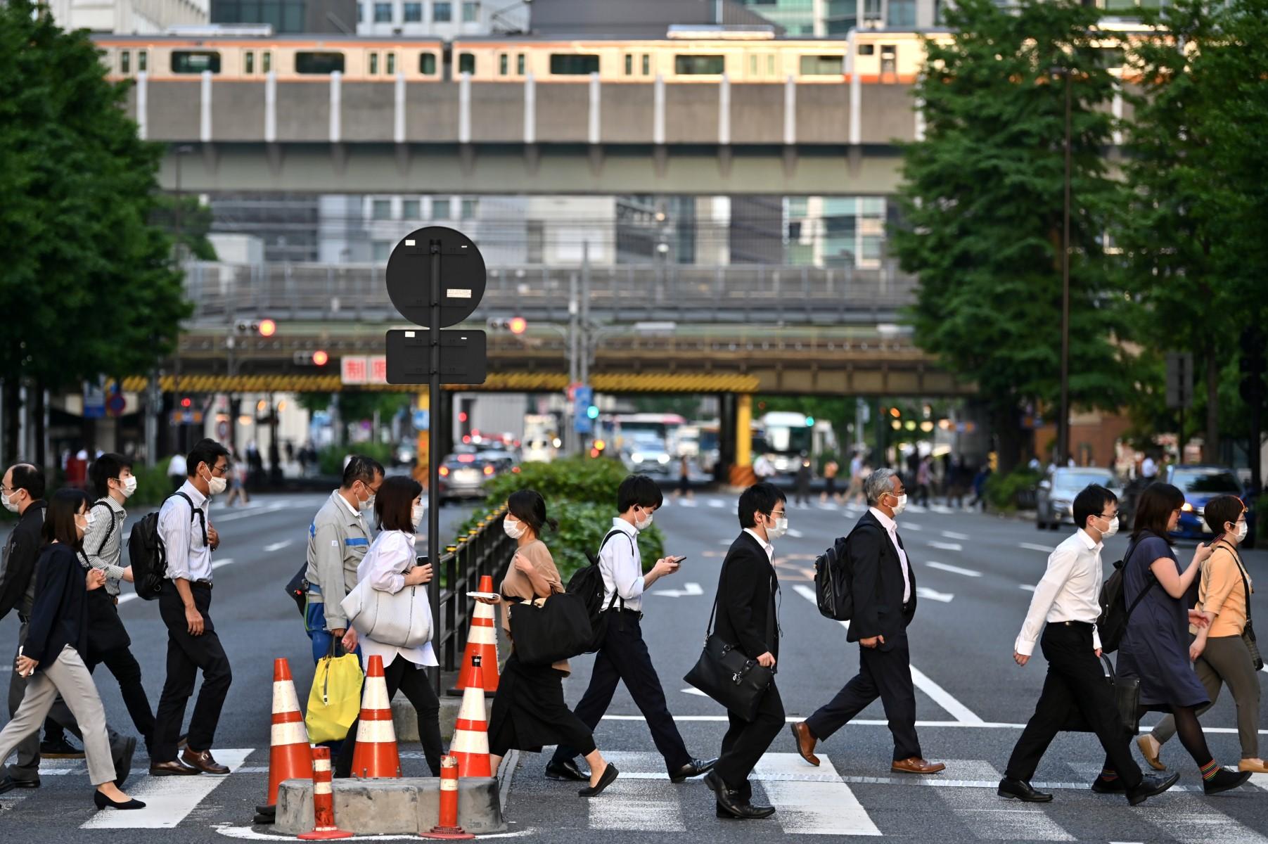Orang ramai memakai pelitup muka ketika menyeberang jalan di Otemachi, Tokyo pada 27 Mei 2020.