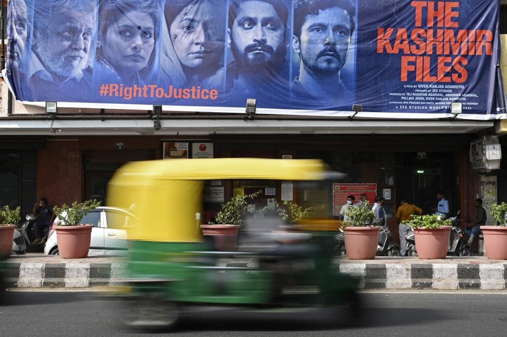 An auto rickshaw moves past a banner of Bollywood movie 'The Kashmir Files' installed outside a cinema hall in the old quarters of Delhi on March 21. Photo: AFP