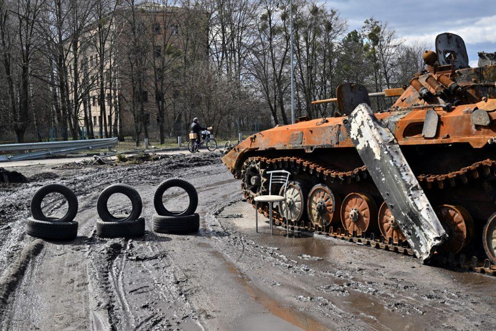 A woman carries her bicycle as she walks past a destroyed Russian armoured personnel carrier in the town of Borodianka, northwest of Kyiv, on April 4. Photo: AFP