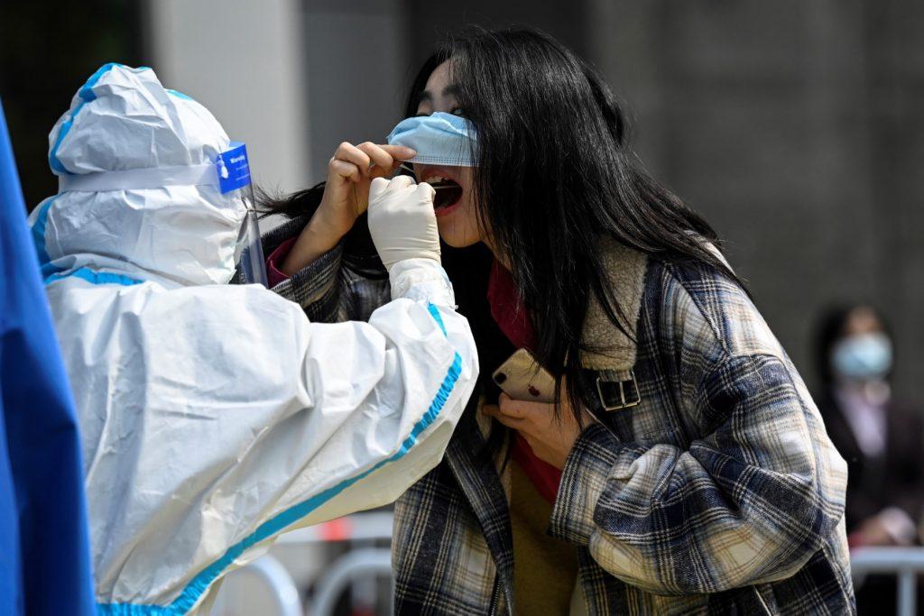 A health worker takes a swab sample from a woman at a Covid-19 coronavirus testing site outside office buildings in Beijing on April 29. Photo: AFP