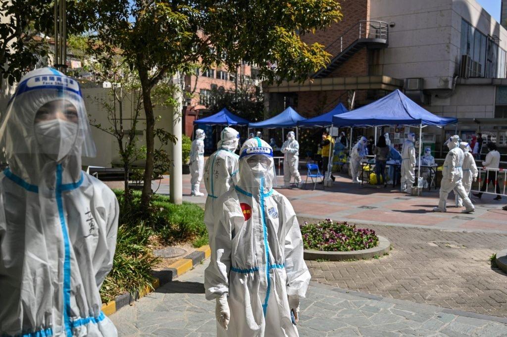 Workers and volunteers look on in a compound where residents are tested for Covid-19, during the second stage of a pandemic lockdown in Jing'an district in Shanghai on April 4. Photo: AFP