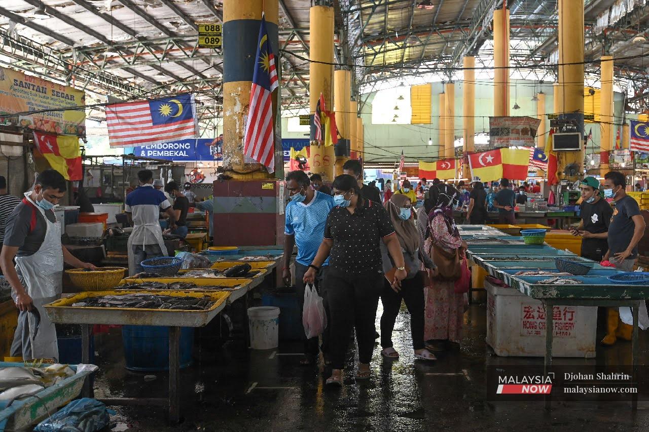 Penjual di Pasar Borong Selangor, Seri Kembangan melayan pelanggan sambil memakai pelitup muka bagi membendung Covid.