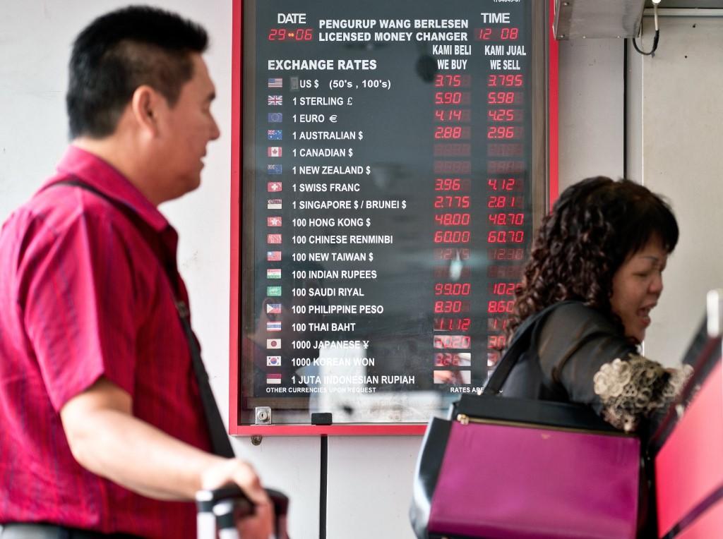 Tourists stand in front of a foreign currency exchange rate display board outside a money changer in Kuala Lumpur in this file picture. Photo: AFP