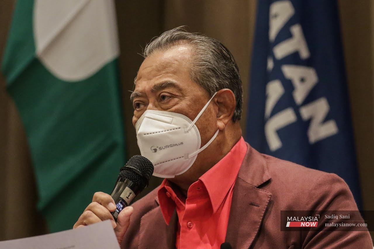 Perikatan Nasional chairman Muhyiddin Yassin speaks at a press conference in January against a backdrop of PAS and PN flags.