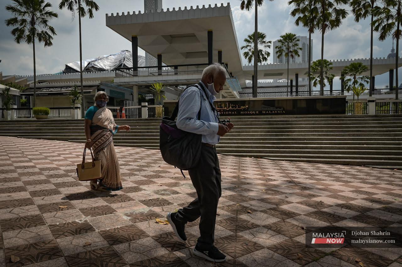 Pelancong dari India berjalan di hadapan Masjid Negara ketika mengunjungi kawasan tarikan pelancong di Kuala Lumpur.