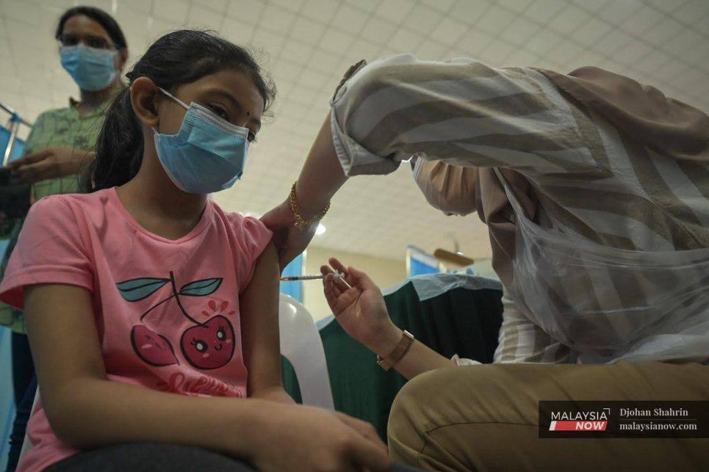 A young girl receives her first dose of Covid-19 vaccine at the Dewan Komuniti Taman Bukit Mewah vaccination centre in Kajang.