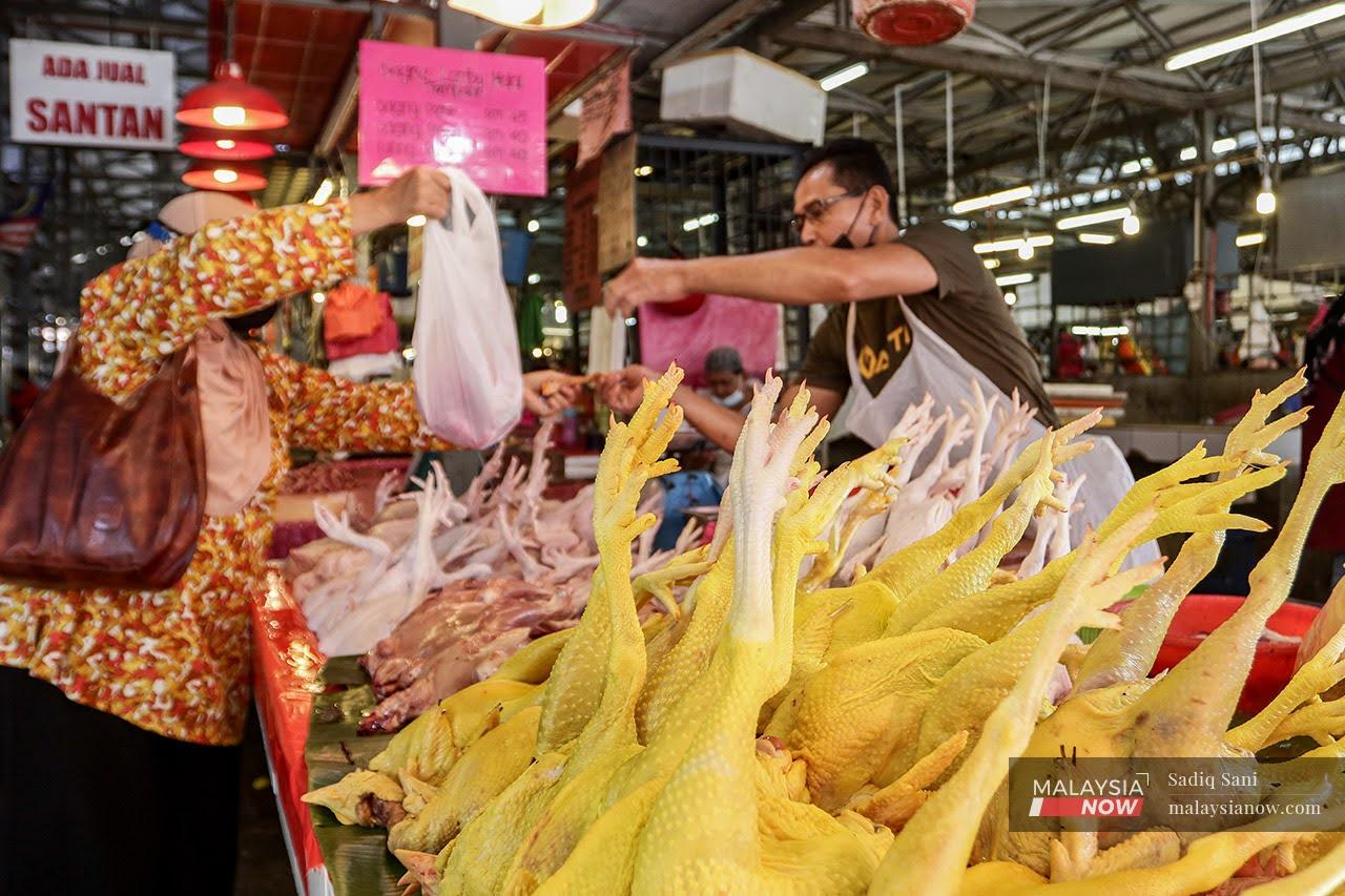 Seorang pembeli mengambil bungkusan ayam yang dibelinya di Pasar Chow Kit, Kuala Lumpur.