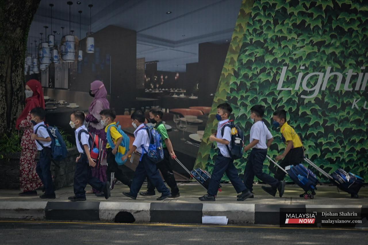 Beberapa murid sekolah berjalan mengikuti penjaga mereka selepas pulang dari sekolah di Jalan Raja Laut, Kuala Lumpur.