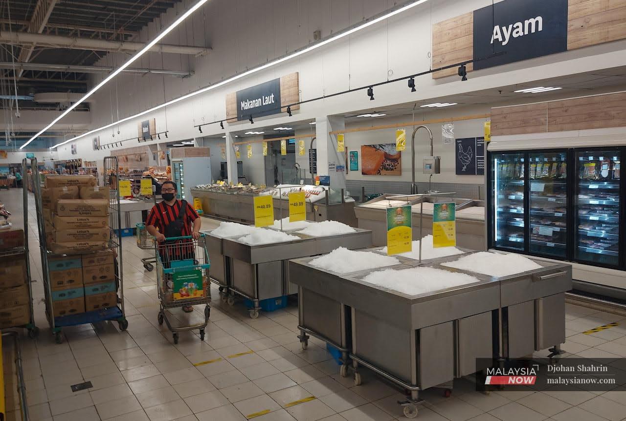 A customer pushes his trolley past the poultry area of a supermarket in Selangor, where only heaps of ice are left. Malaysia has curbed its exports of chicken in order to control soaring prices and combat domestic shortages.