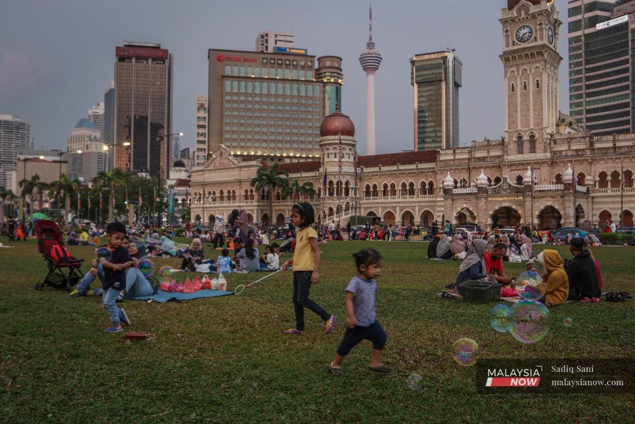 Children play with bubbles as families gather for a picnic dinner in front of the Sultan Abdul Samad building in Dataran Merdeka, Kuala Lumpur.