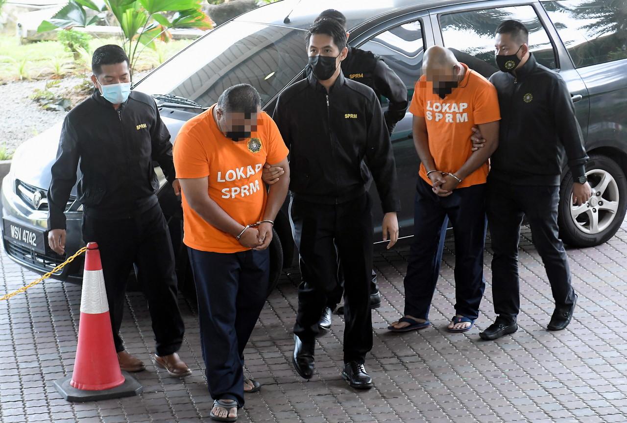 Security personnel escort two assistant health officers who were remanded today to assist in a corruption case involving RM15,000 for funeral arrangement services. Photo: Bernama