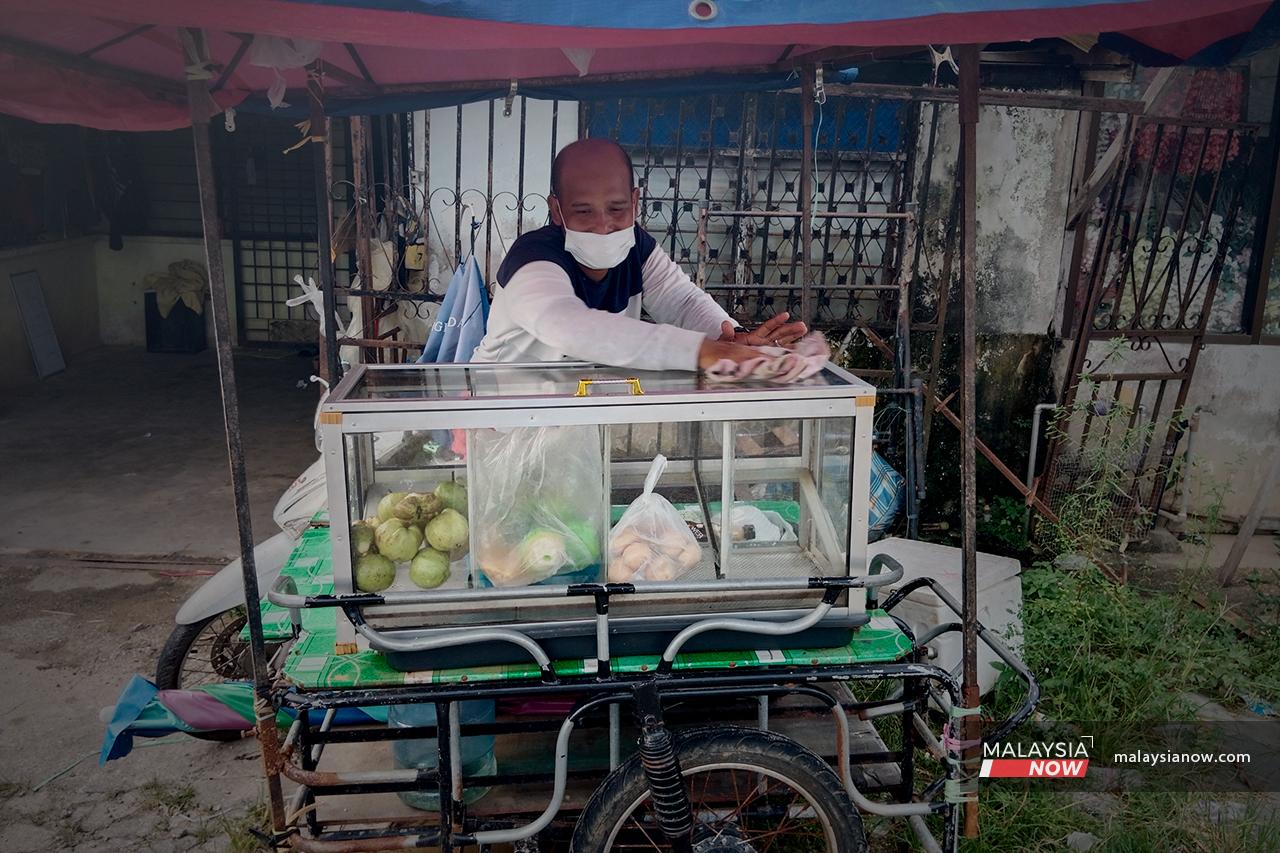 Borhan wipes the top of the clear casing in which he displays the fruit that he sells at his little stall at the side of the road.