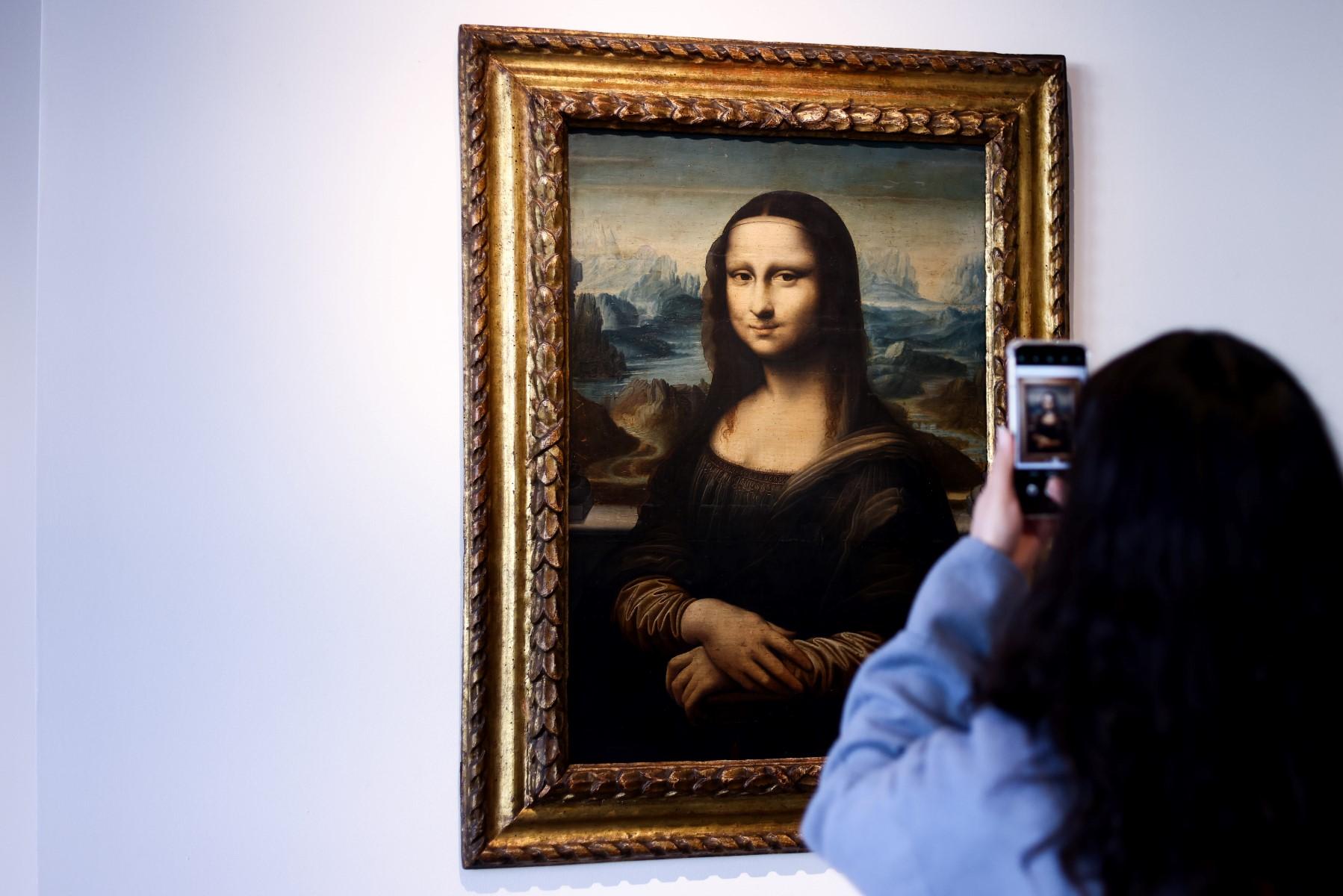 A visitor takes of photo of a copy of Leonardo da Vinci's Mona Lisa, painted around 1600, presented at auction house Artcurial in Brussels on Oct 27, 2021. Photo: AFP