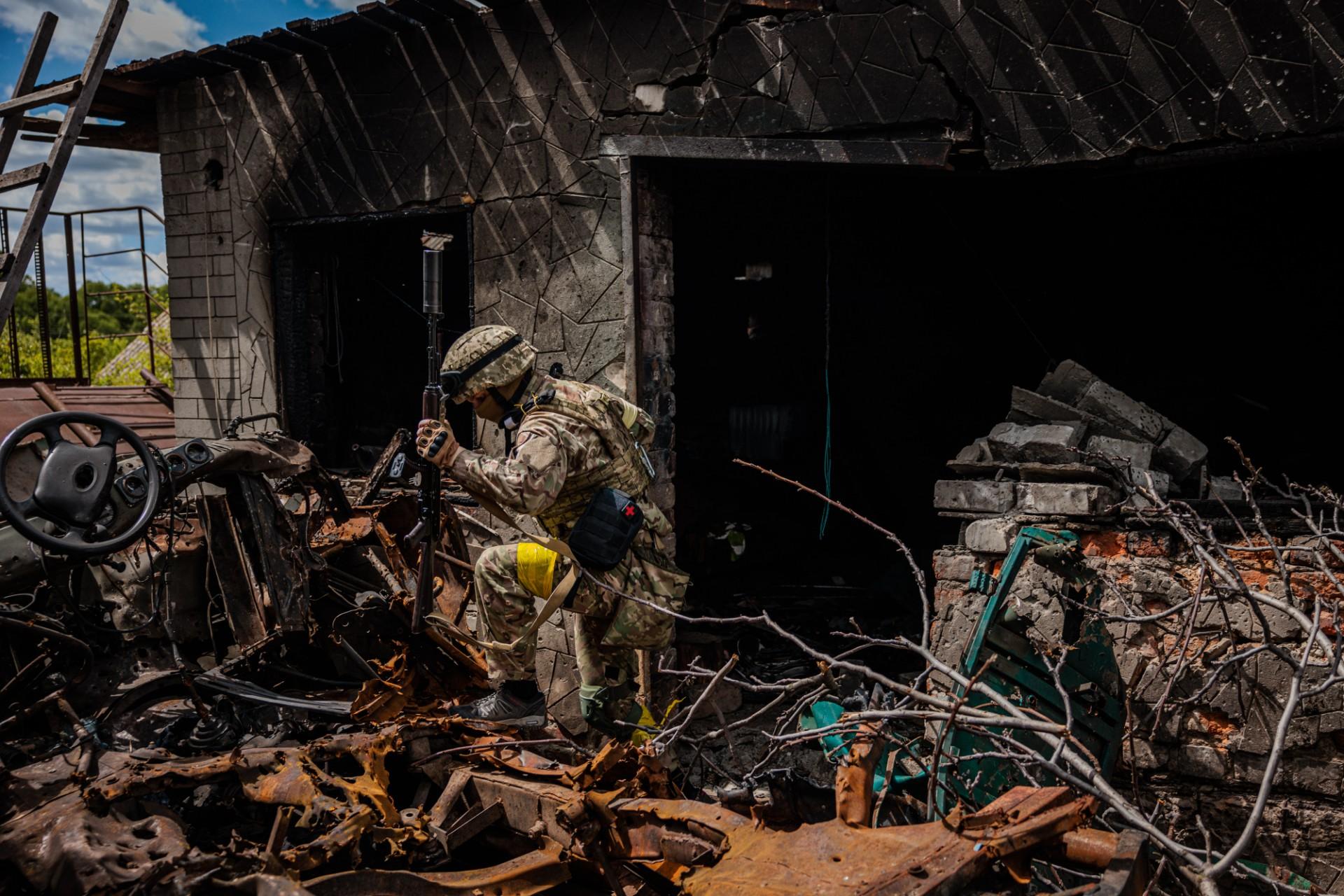 A soldier of the Kraken Ukrainian special forces unit walks past wreckage in the village of Rus'ka Lozova, north of Kharkiv, on May 16. Photo: AFP