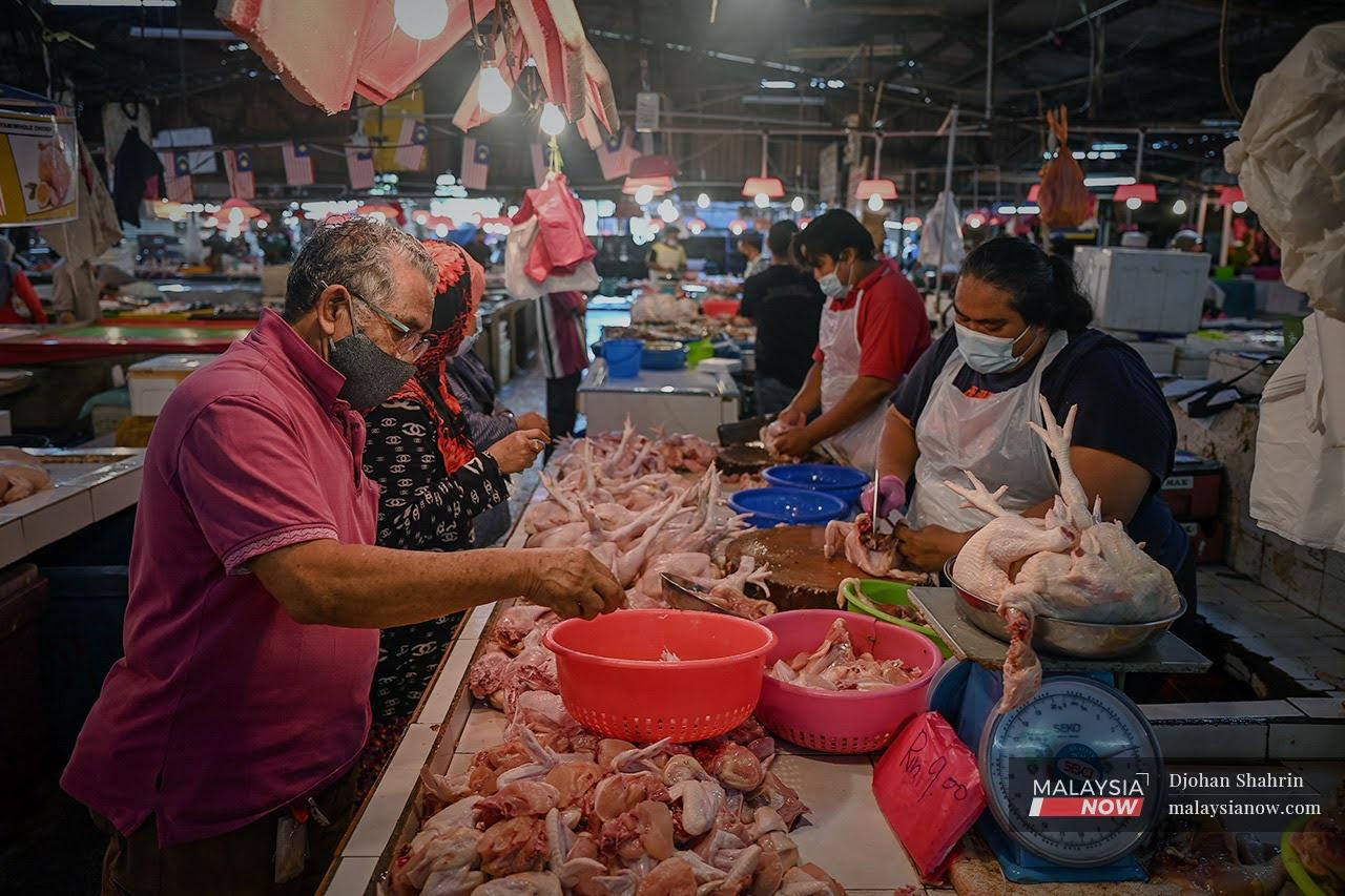 Customers choose chicken at a poultry stall at Pasar Datuk Keramat in Kuala Lumpur.