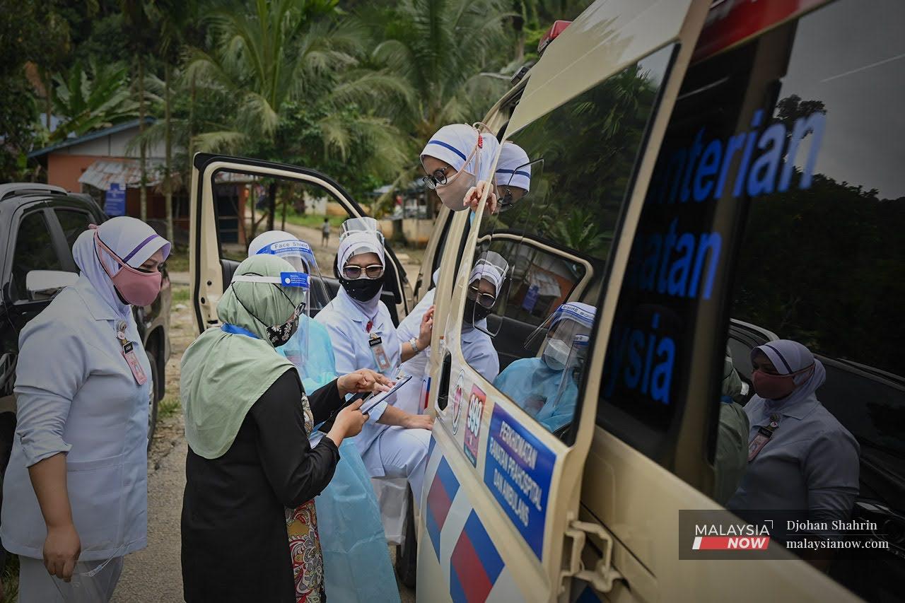 Petugas kesihatan Hospital Orang Asli Gombak berbincang sesuatu semasa program vaksinasi Orang Asli di sekitar daerah Hulu Langat, Selangor.