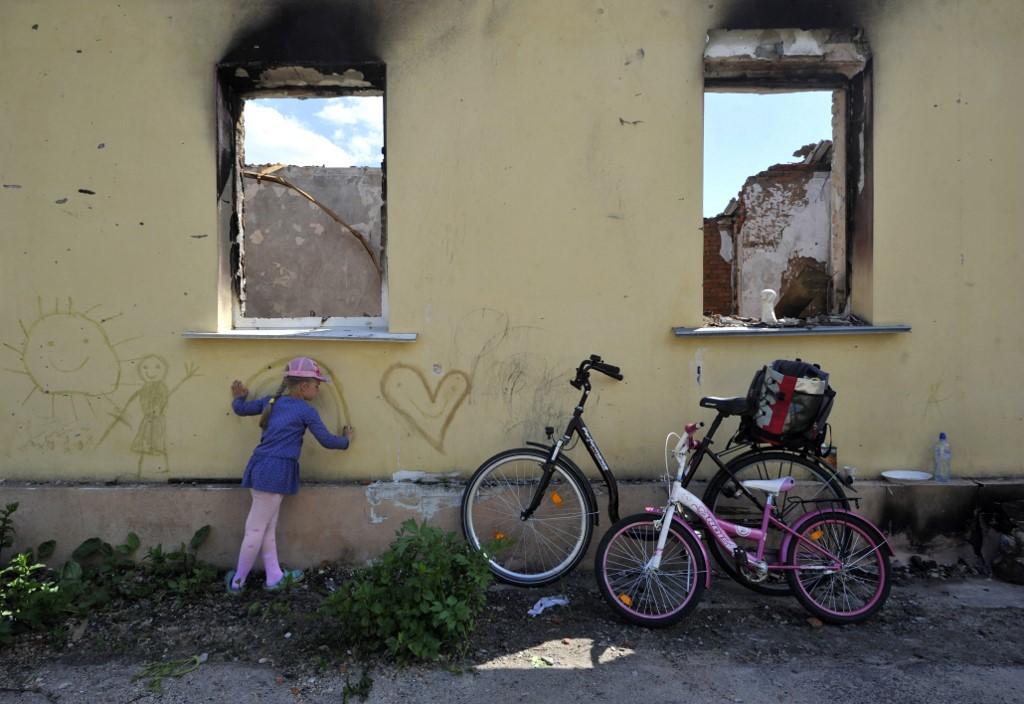 A young girl draws on the wall of a destroyed house in the village of Andriivka, Kyiv region, on June 3, on the 100th day of the Russian invasion of Ukraine. Photo: AFP