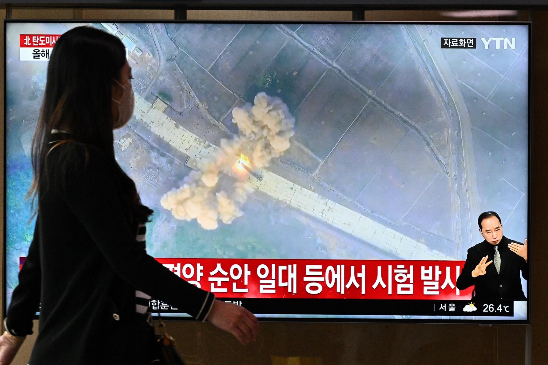 A woman walks past a screen showing a news broadcast with file footage of a North Korean missile test, at a railway station in Seoul on June 5. Photo: AFP