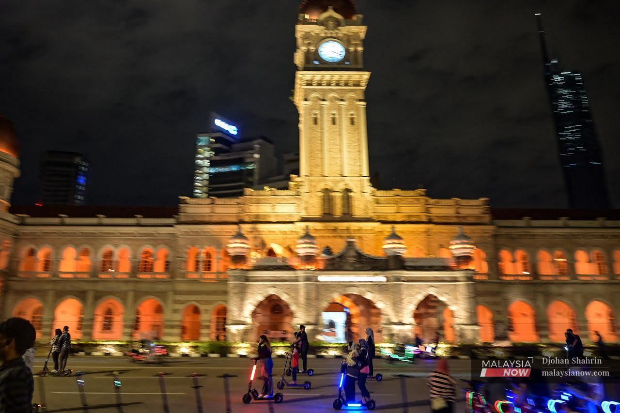 People zoom about on e-scooters despite the late hour at Dataran Merdeka in Kuala Lumpur.