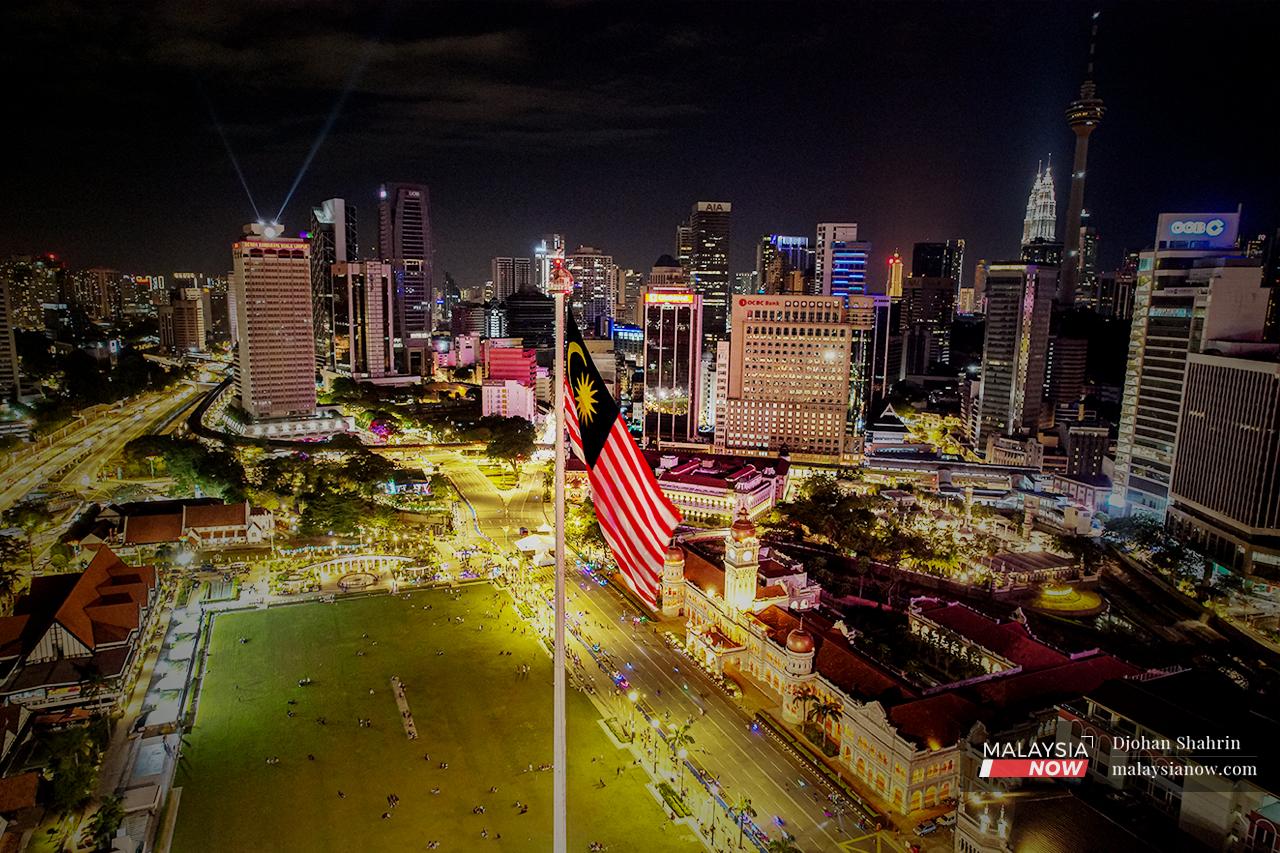 A Malaysian flag flutters in the night breeze above the crowds of people who have come to enjoy an evening – and more – at Dataran Merdeka in the heart of the capital city.