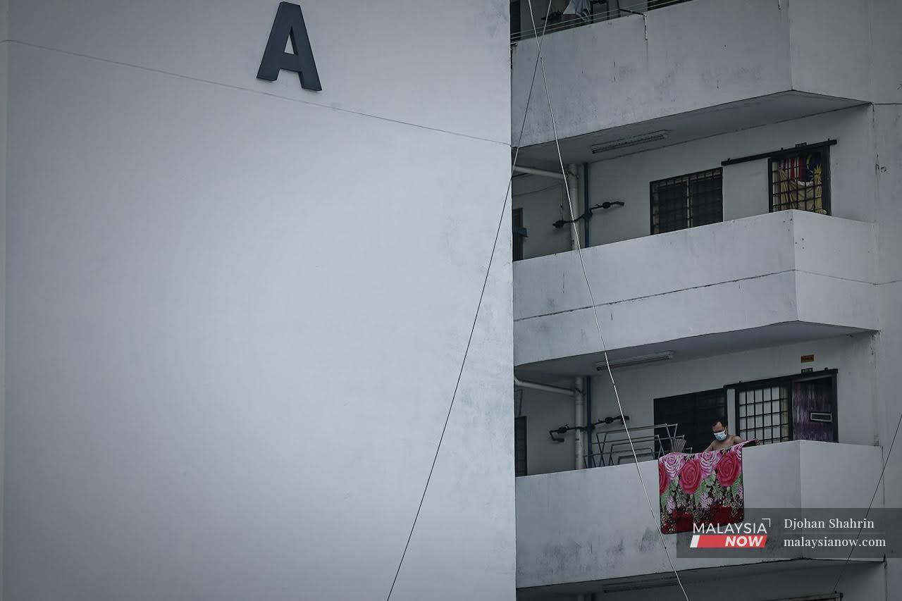 A man hangs a carpet out to dry on the balcony of the corridor outside his unit at a low-cost housing project in Kuala Lumpur.
