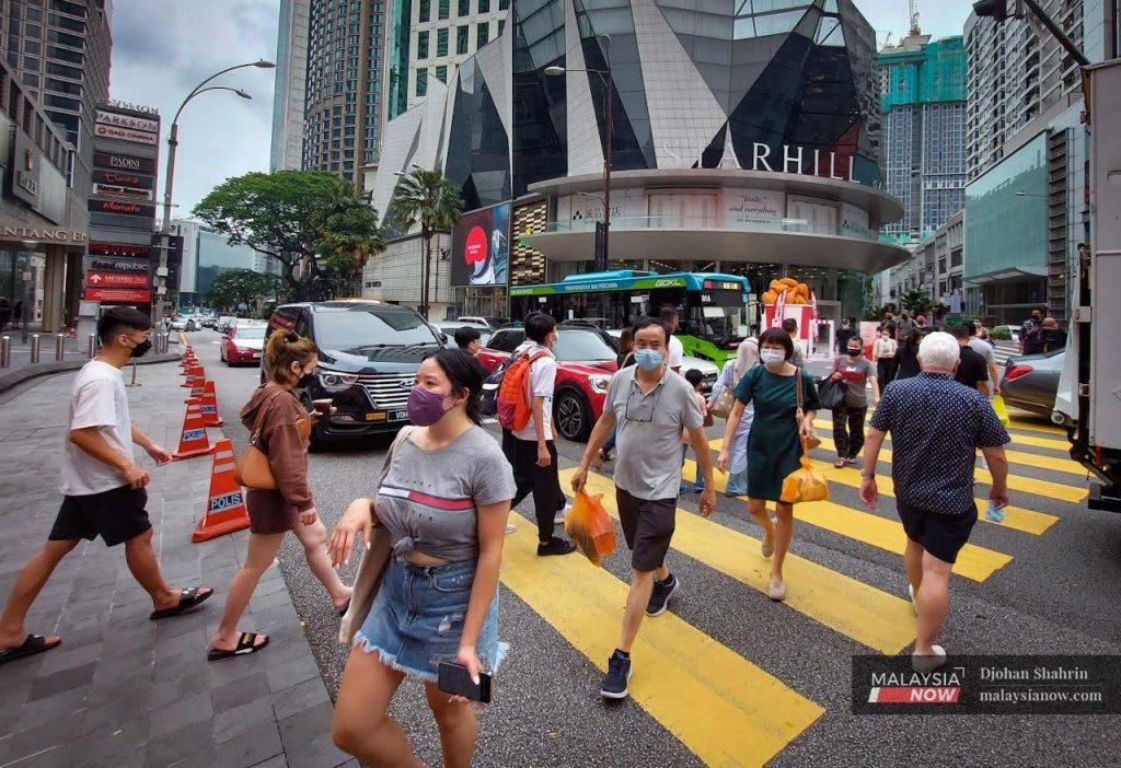 Pedestrians wearing face masks cross a road in the Bukit Bintang district in Kuala Lumpur.