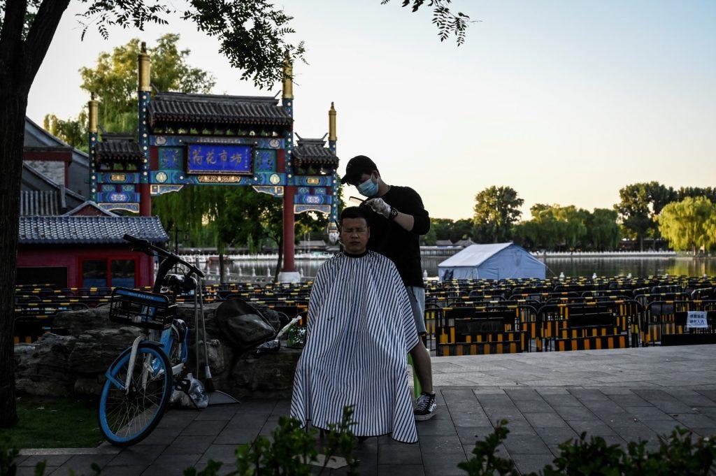 The photo taken on May 25, shows a man geeting his haircut outside a park on a street in Beijing. Photo: AFP