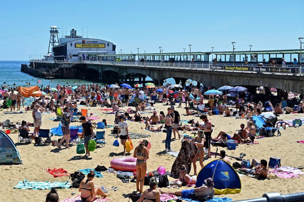 Pengunjung berjemur dan mandi-manda pantai Bournemouth, selatan England pada 25 Jun 2020. Gambar: AFP