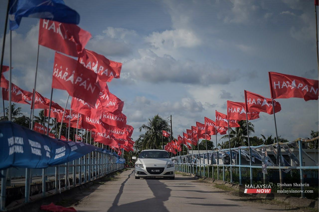 Sebuah kereta melalui deretan perang bendera antara Perikatan Nasional, Barisan Nasional dan Pakatan Harapan di Bukit Rambai ketika Pilihan Raya Negeri Melaka tahun lalu.