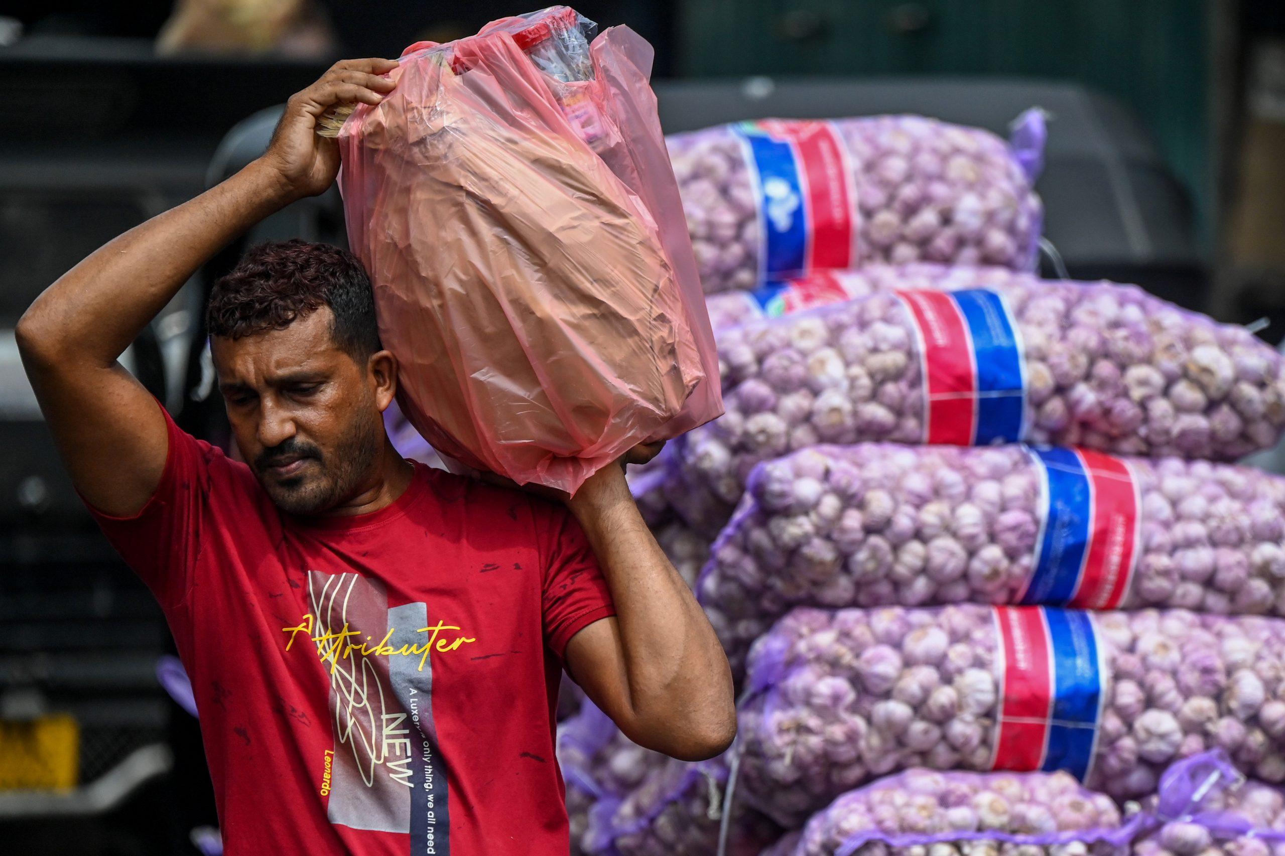 Workers transport food grains and other essential goods at a market after authorities relaxed the ongoing curfew for a few hours in Colombo on May 12. Photo: AFP