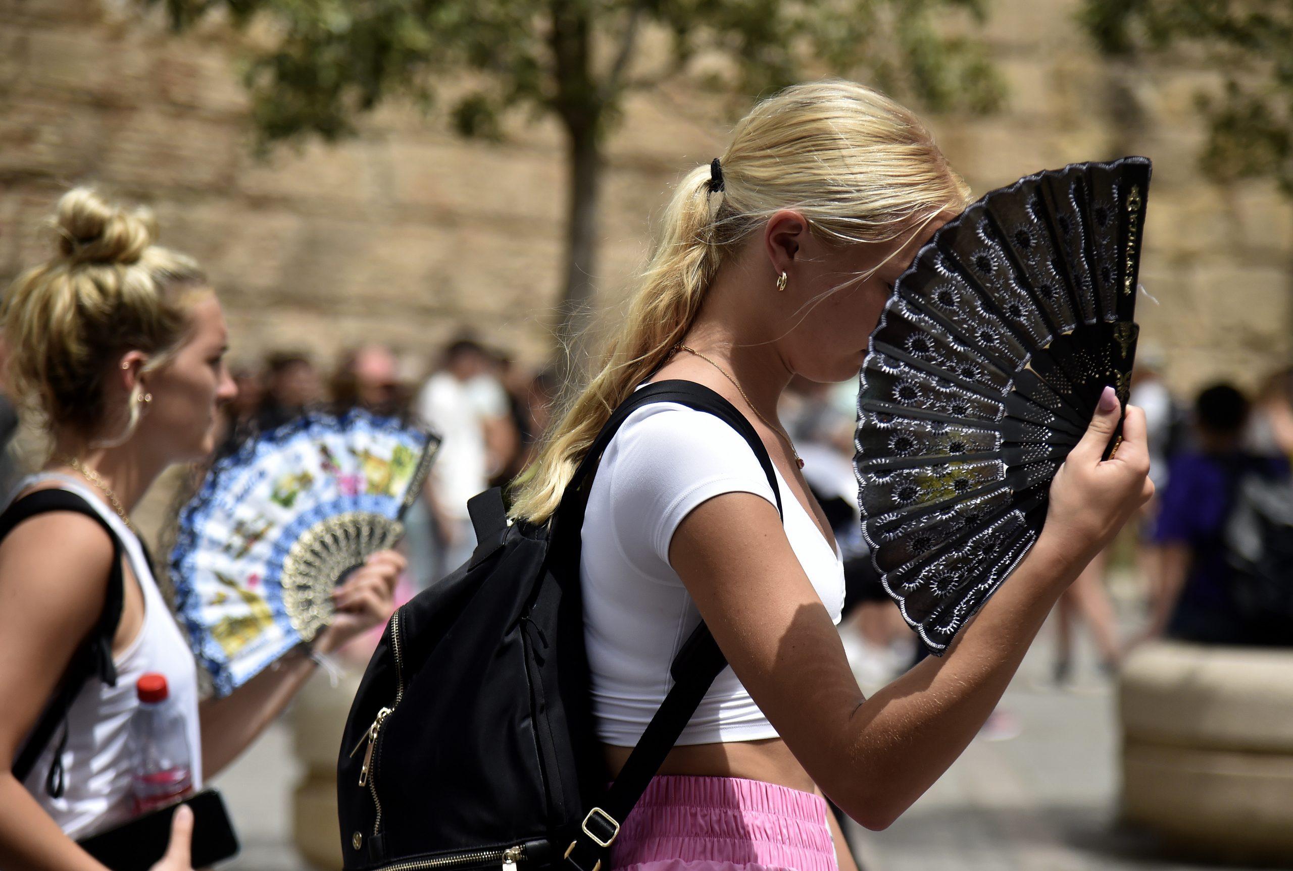 Dua orang wanita menggunakan kipas tangan di tengah cuaca panas dan kering yang melanda Sepanyol sejak Jun lalu. Gambar: AFP