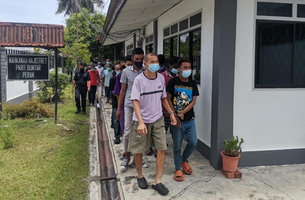 Ng Yu Lim (second right) is escorted out from the Parit Buntar Magistrate’s Court after being charged with murdering his mother and hacking her body into 15 pieces. Photo: Bernama