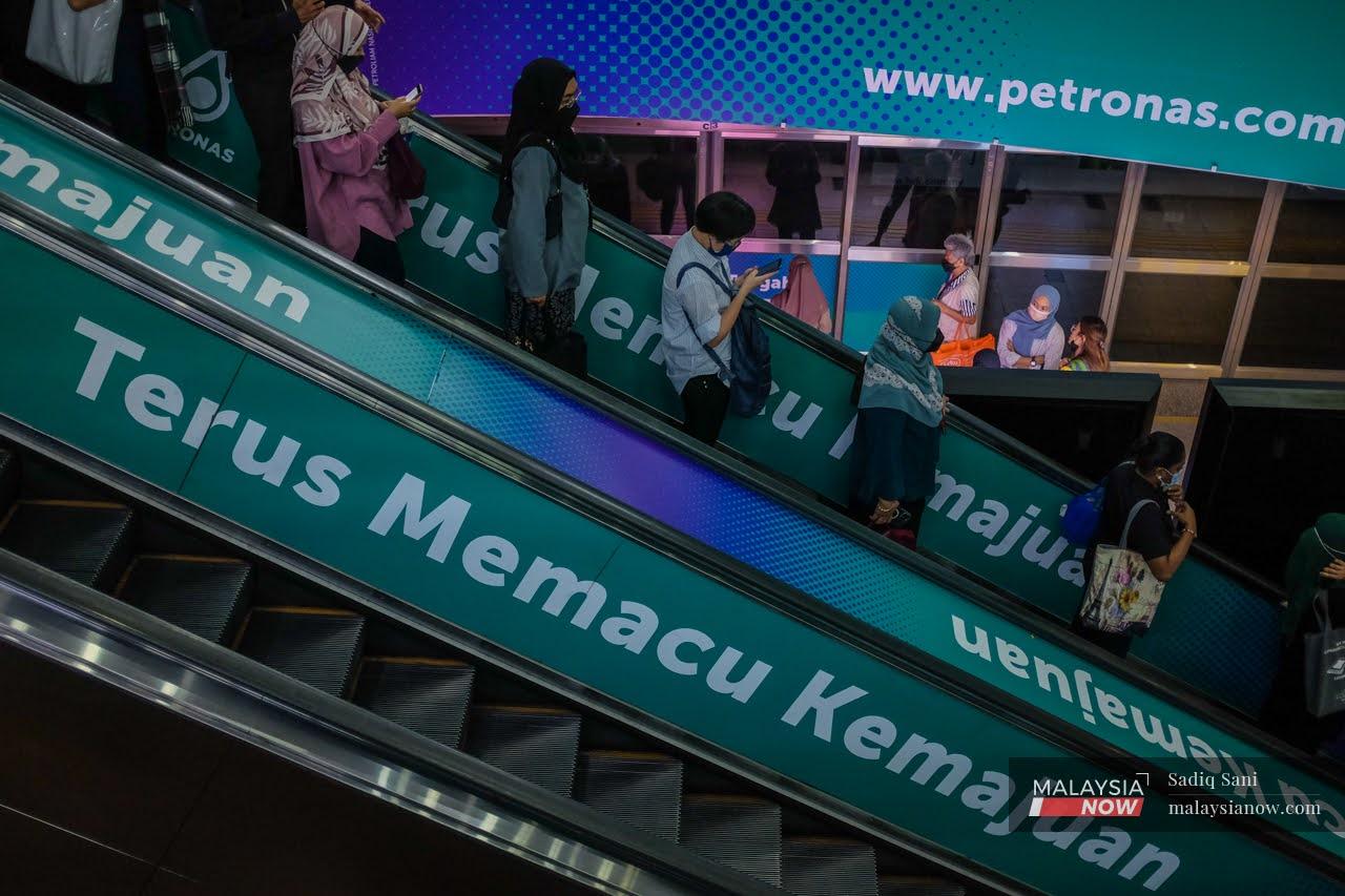 Commuters wearing face masks take the escalator down at the KLCC LRT station after a day of work in Kuala Lumpur.
