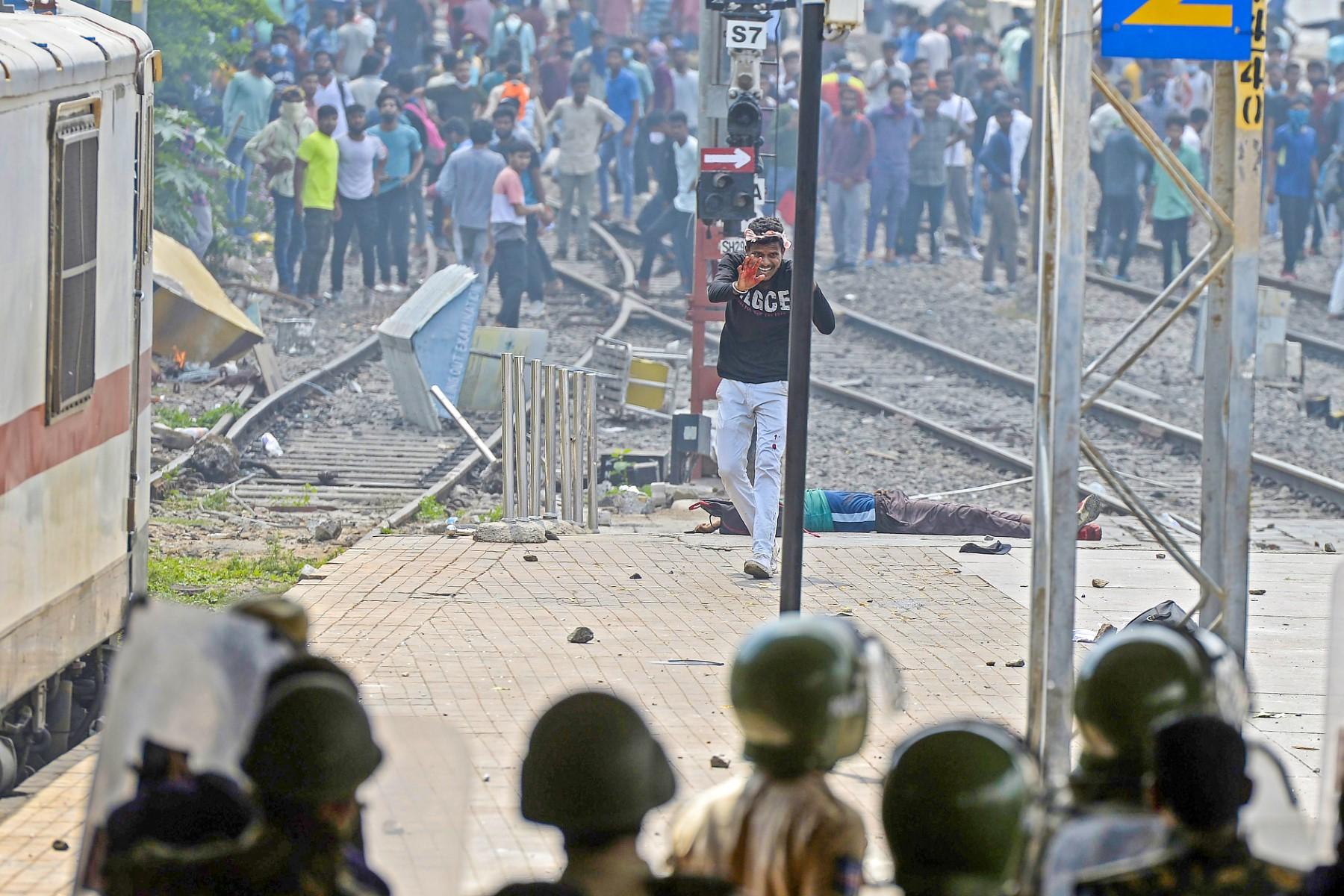 A protester reacts in front of a wounded man after police opened fire to disperse protesters during a demonstration against the government's new recruitment scheme for the army, navy, and air forces at a railway station in Secunderabad on June 17. Photo: AFP