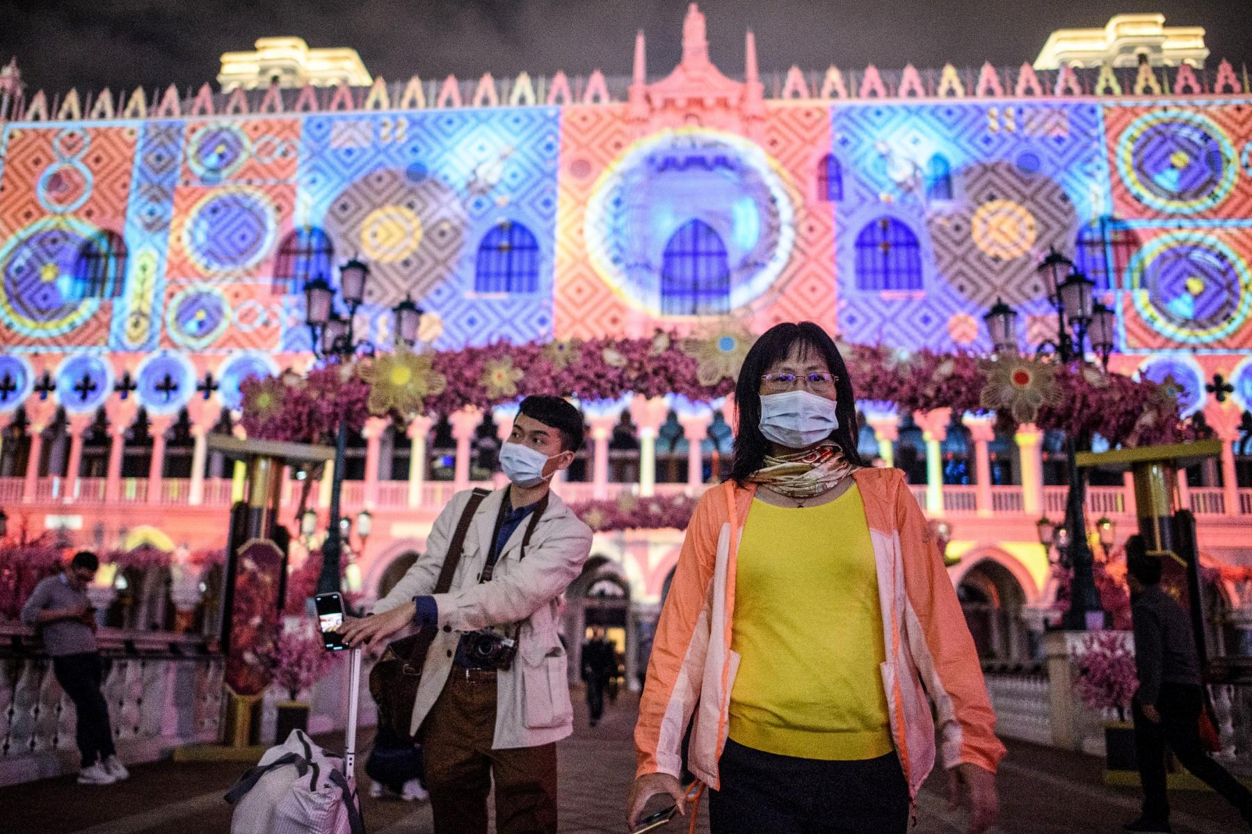 Visitors wear face masks as they walk outside the Venetian casino hotel resort as a Lunar New Year light display is projected upon a facade of the building in Macau on Jan 22, 2020. Photo: AFP