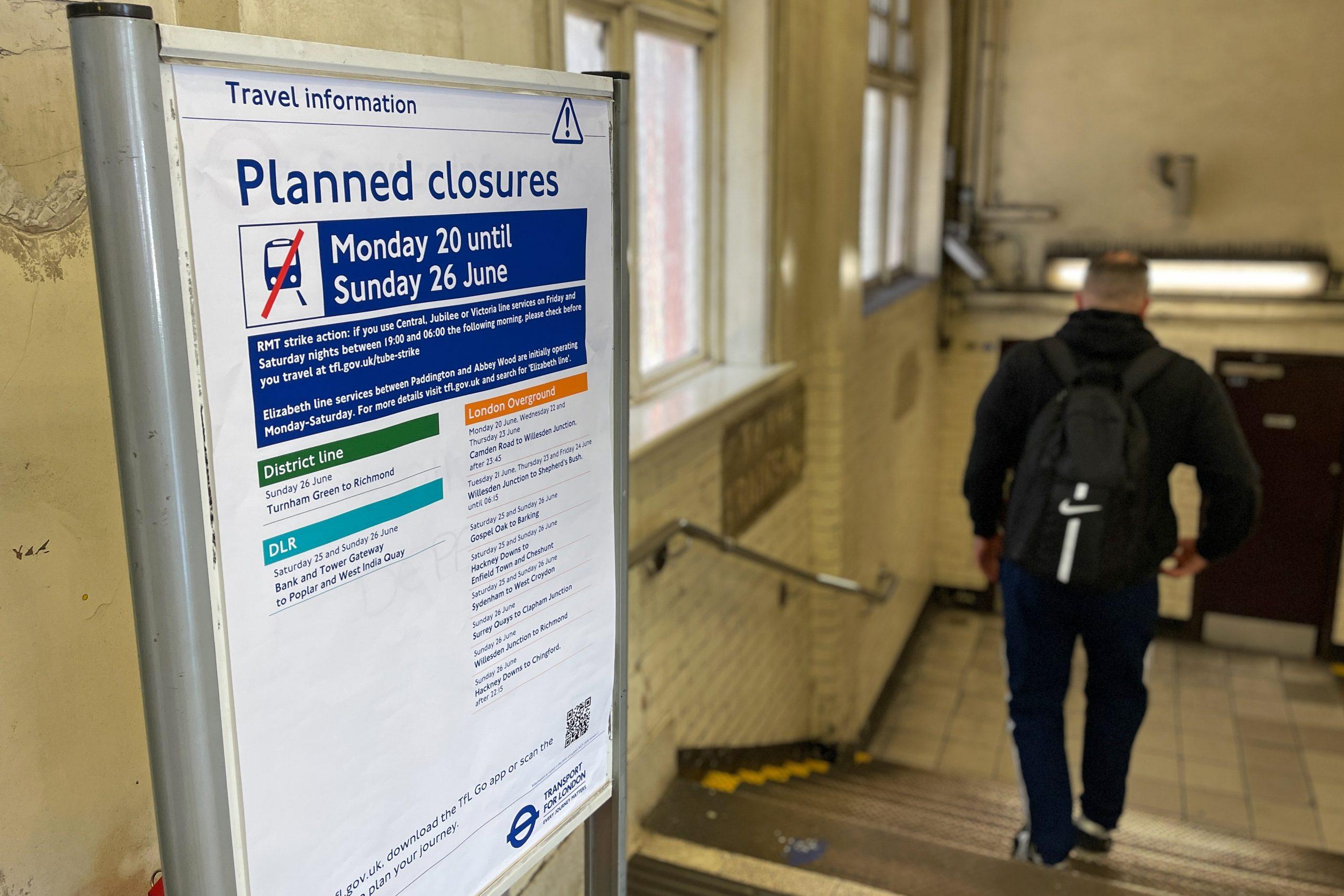 A passenger passes an information sheet displayed outside Stepney Green station in east London, on June 20, advising the public on strike action on National Rail and London Underground the following day. Photo: AFP