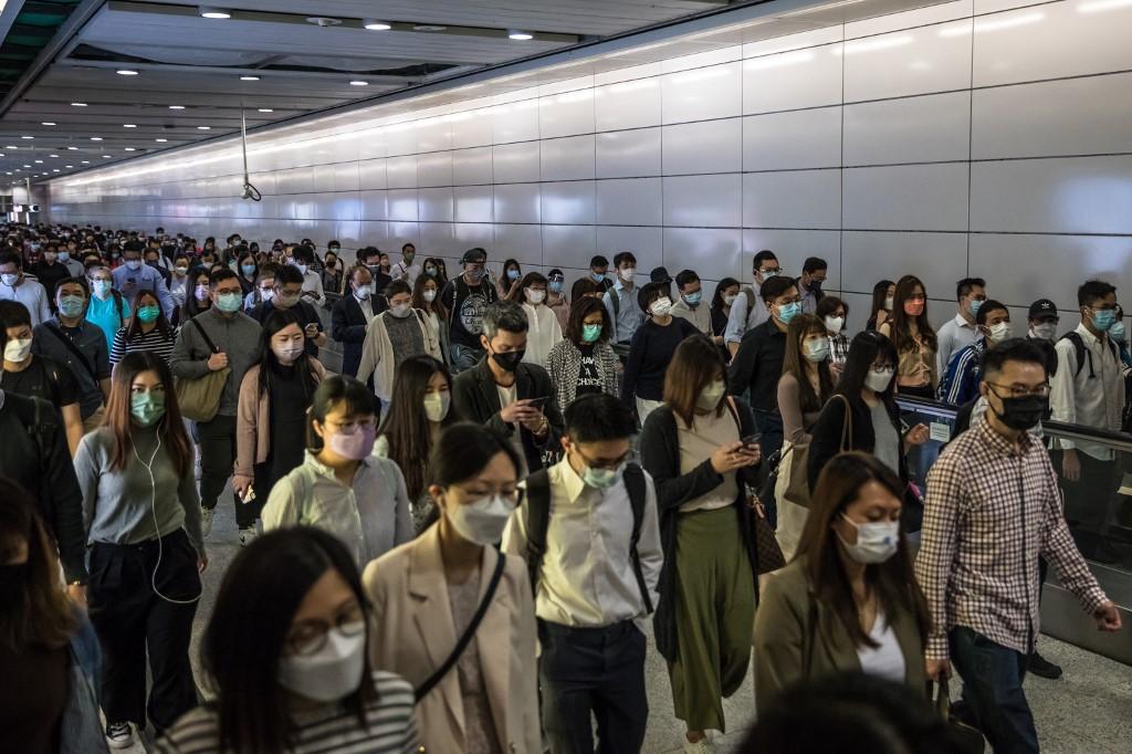 People wearing face masks as a preventive measure against the Covid-19 coronavirus walk through a train station in Hong Kong on March 21. Photo: AFP