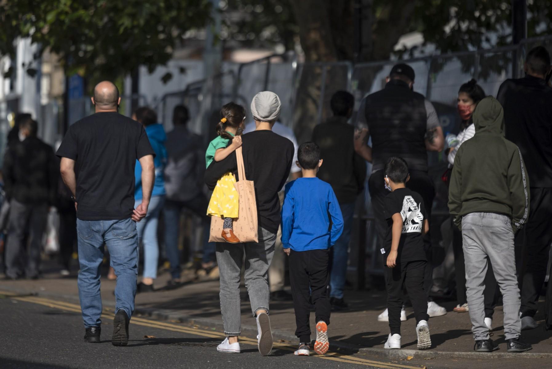 A family with young children walk past the queue to a Covid-19 testing centre in Edmonton in north London, on Sept 17, 2020. Photo: AFP