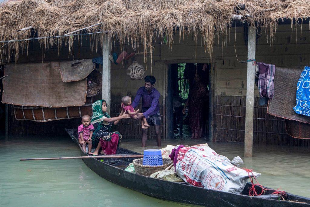A woman holds her child as they evacuate their house submerged in a flooded area following heavy monsoon rainfalls in Goyainghat on June 19. Photo: AFP
