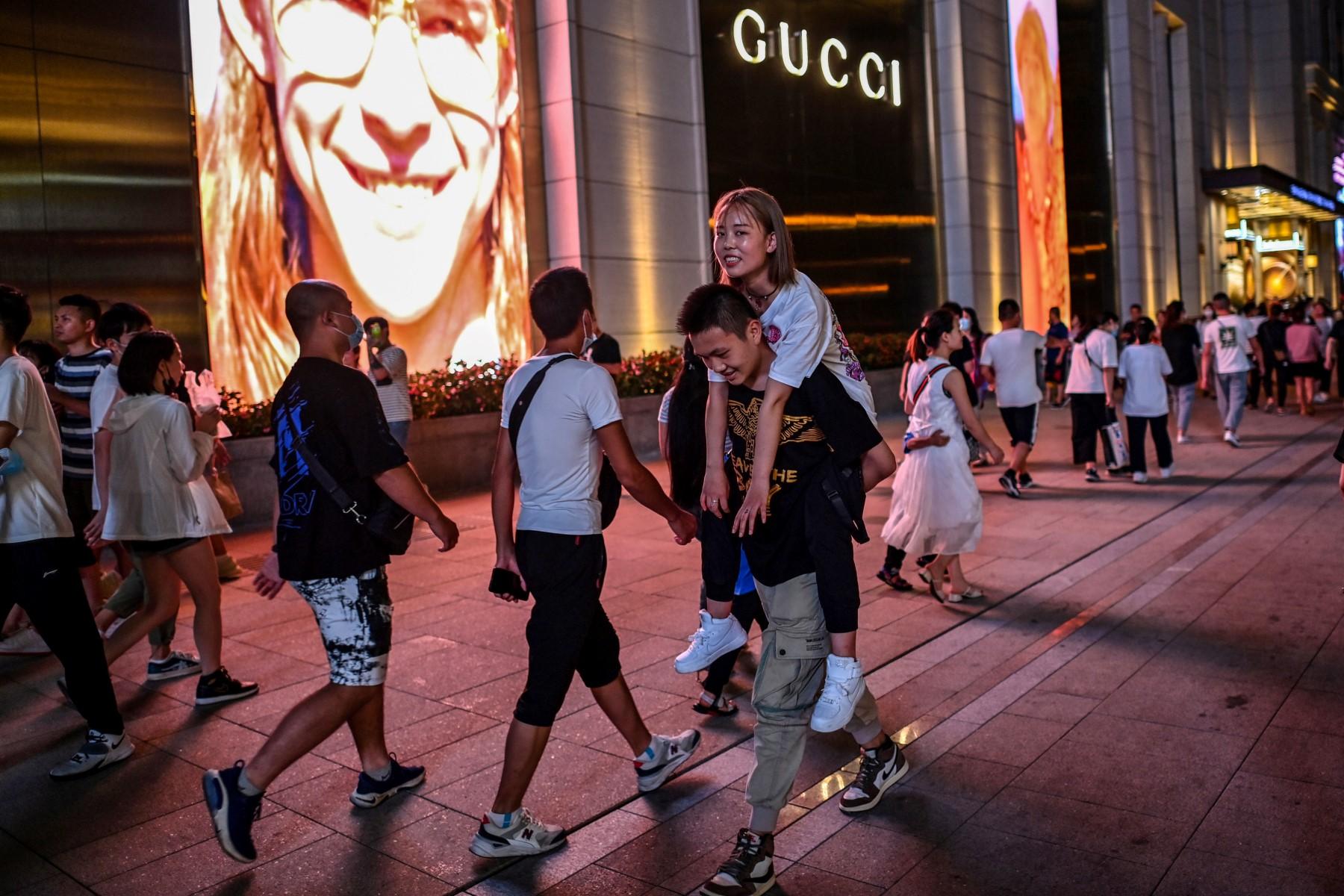 A man carries a woman piggyback on a street surrouned by shops and malls in Shanghai on July 31, 2020. Photo: AFP