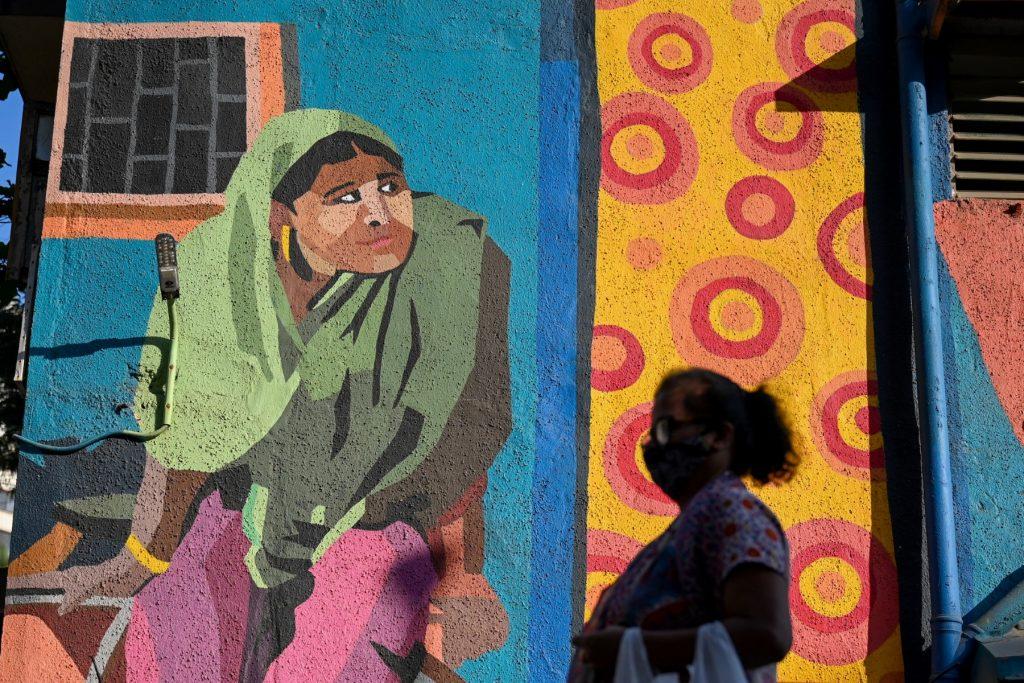 A woman walks past a mural portraying daily life in the Dharavi slums in Mumbai on Feb 22. Photo: AFP