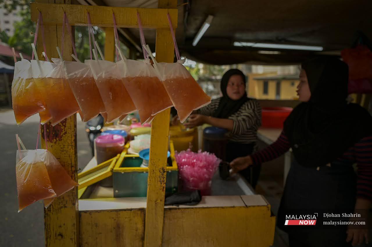 Workers at Huri Teh Tarik Dangdut chat as they prepare the bags of ice cold tea which have customers queuing from morning to night.