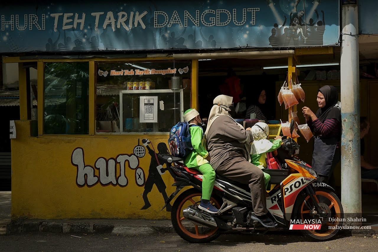 Seorang pekerja warung Huri Teh Tarik Dangdut di Taman Medan menyerahkan pesanan kepada pelanggan. Harga murah air minuman ikat tepi yang dijualnya menjadi tarikan sejak 20 tahun lalu.