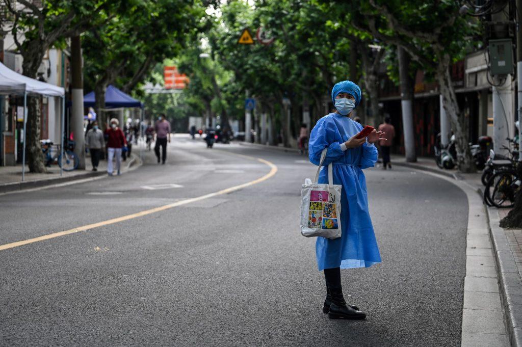 A woman wearing protective gear stands on a street during a Covid-19 lockdown in the Jing'an district of Shanghai on May 25. Photo: AFP