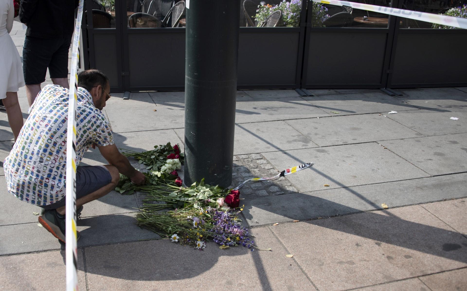 A man lays flowers at the crime scene on June 25, in the aftermath of a shooting outside pubs and nightclubs in central Oslo which killed two people and injured 21. Photo: AFP